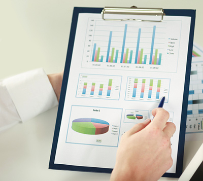 A person points to graphs on a clipboard